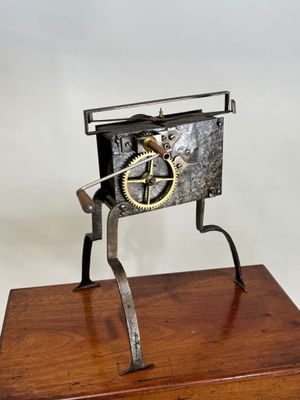 une image représentant une horloge en métal et en bois posée sur un socle en bois