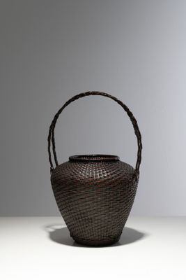 panier en osier marron muni d'une poignée, posé sur un fond blanc