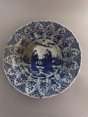 a blue and white plate with a picture of people on it