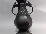 a bronze vase with a handle on a pedestal