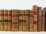 several old books are lined up in a row on a white surface