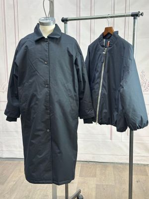 une paire d'imperméables noirs suspendus à un porte-manteau devant un mur