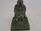 figurine en bronze représentant un homme assis sur un rocher