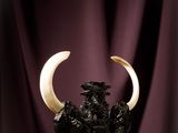 sculpture of a bull with horns on a wooden table with a purple curtain in the background