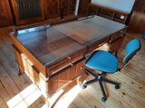 a desk with a glass top and a blue chair in a room