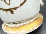 a close up of a vase on a table with a clock on it