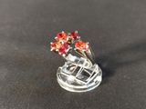 silver ring with red stones on top of it on a black surface