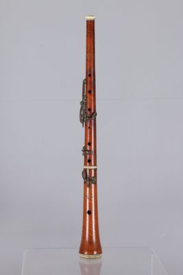 a close up of a clarinet on a clear surface with a gray background