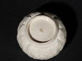 a small white vase sitting on a black surface
