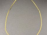 a gold necklace on a gray surface with a black background