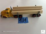 un camion jouet jaune avec un long chargement de rondins à l'arrière