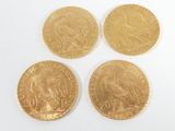 four gold coins are shown on a white surface with a white background