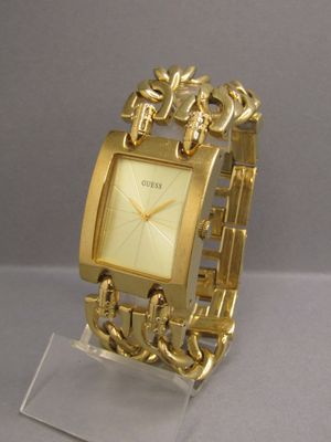 a gold watch on a clear stand on a gray surface