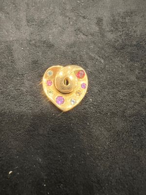 a gold heart shaped pin with pink and blue stones on it