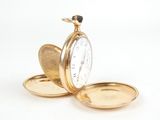 a gold pocket watch sitting on top of a white surface