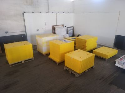 Plusieurs cartons jaunes sont empilés sur des palettes dans un entrepôt