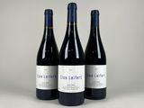 three bottles of red wine sitting next to each other on a table