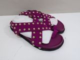 purple and white sandals with gold studding on them sitting on a white surface