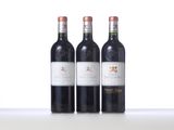 three bottles of red wine are lined up on a table