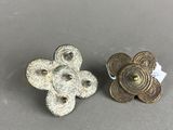 a pair of small metal buttons on a gray surface