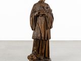 a wooden statue of a man holding a dog on a pedestal