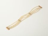 a close up of a pearl bracelet on a white surface
