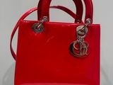 a red handbag with a silver logo on the handle