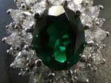 a close up of a green and white diamond ring on a table