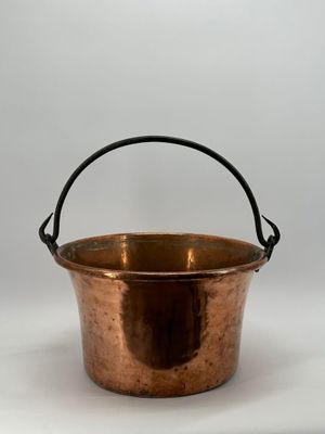 une vieille casserole en cuivre avec une poignée, sur fond blanc