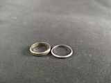 two wedding rings sitting on top of a table next to each other