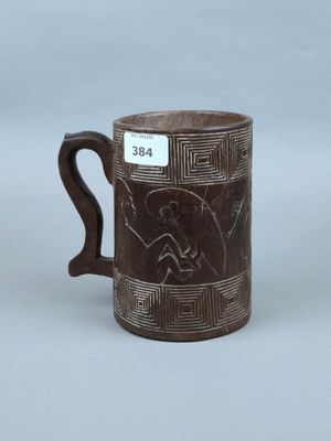 une vieille tasse marron décorée d'un motif, posée sur une table