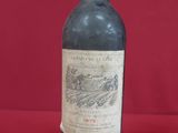 an old bottle of wine sitting on top of a red table