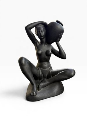 statue of a woman sitting on a rock with a pot on her head