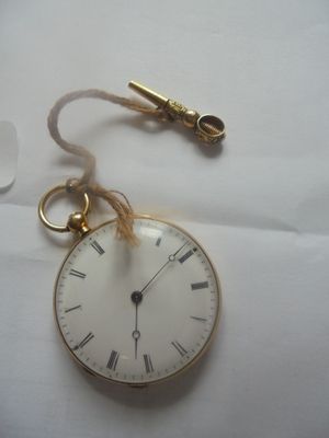 une montre de poche en or à laquelle est accrochée une chaîne sur le côté