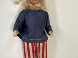 an old fashioned doll with blonde hair and red and white striped pants
