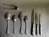 five spoons, a fork, and a knife on a table