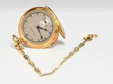 une image représentant une montre de poche en or avec une chaîne, posée sur une surface blanche