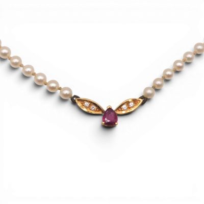 un gros plan sur un collier orné de perles et d'un rubis