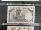 Trois billets de banque différents sont exposés dans une vitrine.