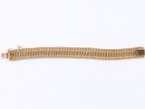 a close up of a gold bracelet on a white surface
