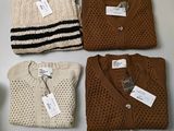 three pairs of sweaters are on a table with tags on them