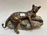a bronze statue of a dog laying on a rock