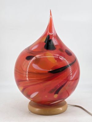 a red and black glass vase on a wooden stand