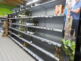 many empty shelves in a store with bottles of wine