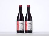 two bottles of red wine sitting on top of a table
