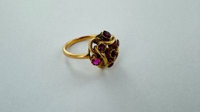 Gros plan sur une bague en or ornée de pierres roses