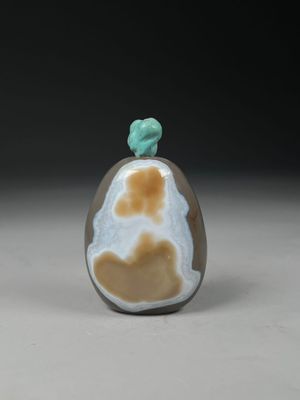 une petite bouteille en verre ornée d'un motif marron et blanc
