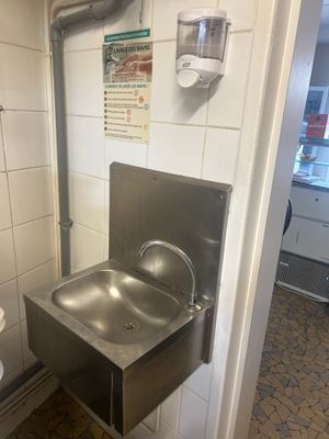 a stainless steel sink in the corner of a bathroom