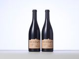 two bottles of red wine sitting on top of a table