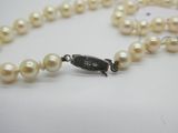 collier de perles blanches avec un fermoir en argent et un fermoir noir